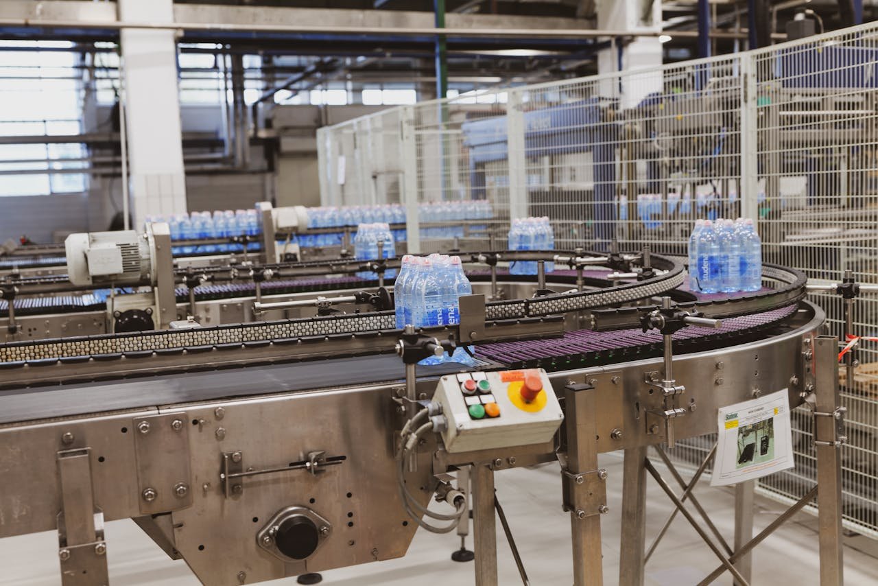 gallery-5 Water bottles being processed on an automated conveyor in a modern factory setting.